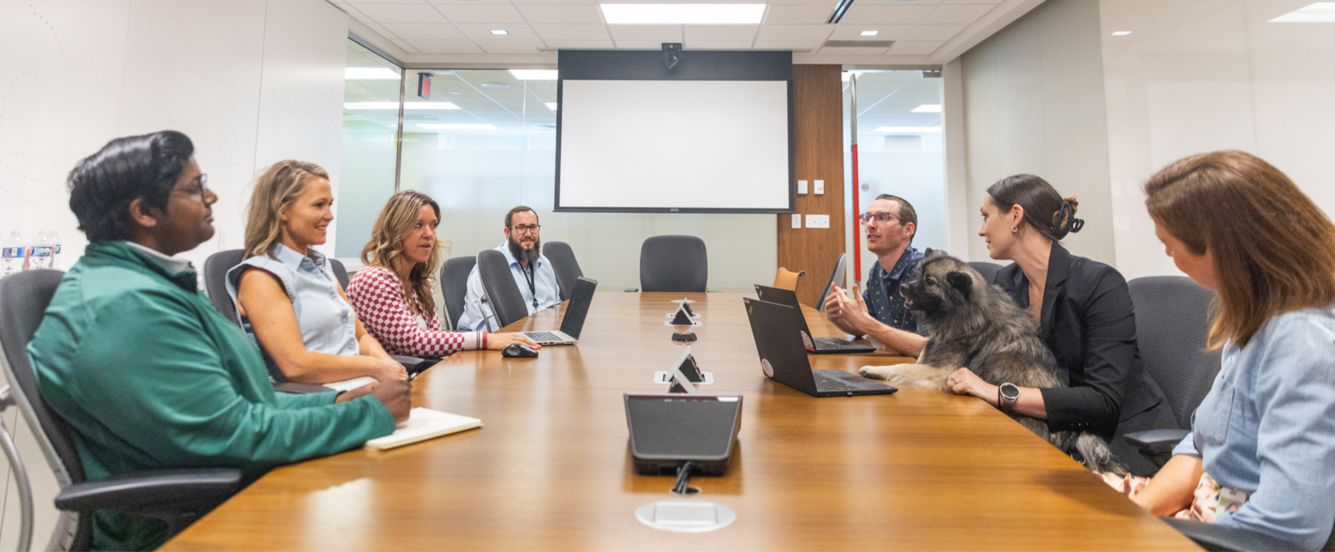 Nestlé Purina associates sit and talk in a meeting room while one associate has a dog on their lap