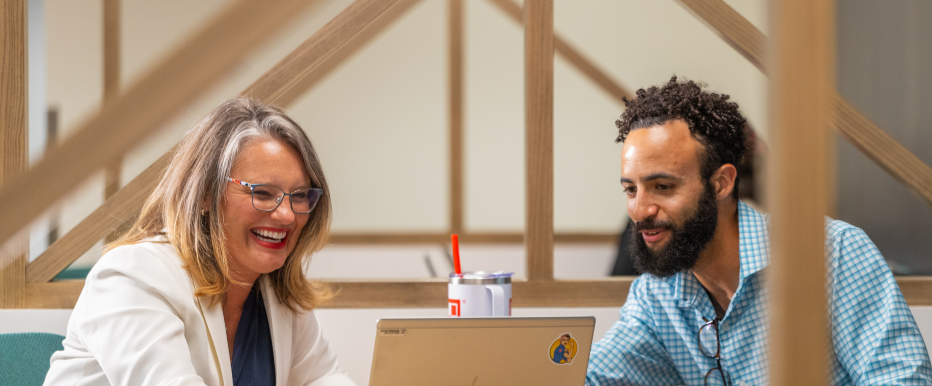 Two colleagues laugh while discussing topics in a meeting at Nestlé office